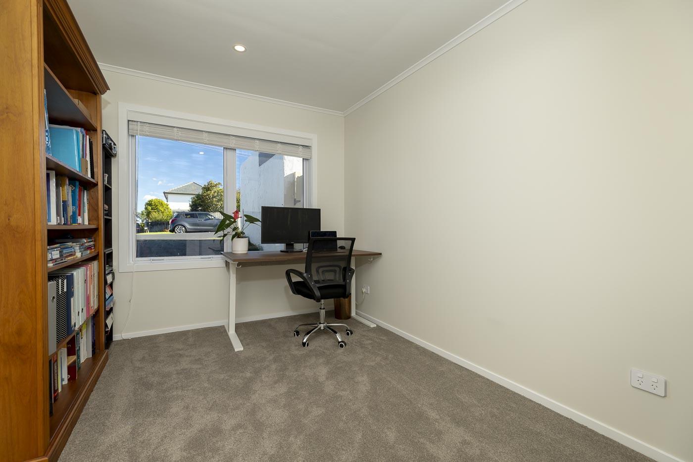 A renovated home office with a wall-mounted desk, bookshelves and a street-facing window.