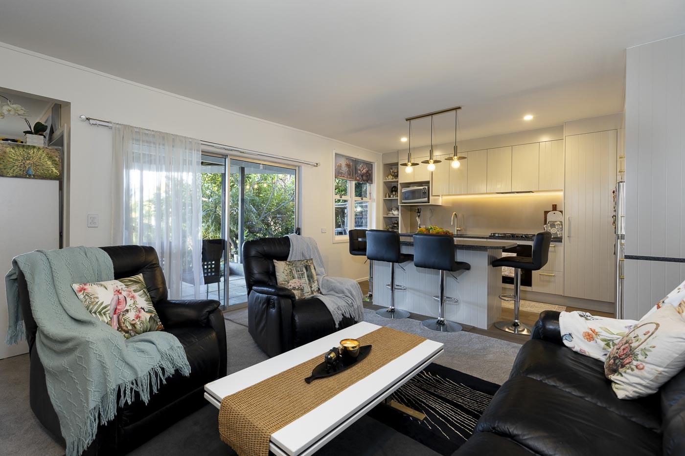 The same space after renovation: an open-plan kitchen with a breakfast bar flowing into the living area.
